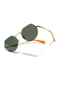 Ochelari de soare cu rame din metal aurii, cu lentile verzi, de formă octagonală și brațe din acetat portocalie. Include pernuțe pentru nas pentru confort.