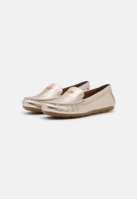 Metalické zlaté loafers s texturovaným povrchem, prošívaným předním dílem a designem na obouvání. Gumové podrážky a nenápadné logo na přední straně.
