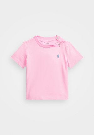 Jasnoróżowy niemowlęcy t-shirt z krótkim rękawem, dwoma zatrzaskami na ramieniu i małym niebieskim wyszywanym logo Polo na piersi.
