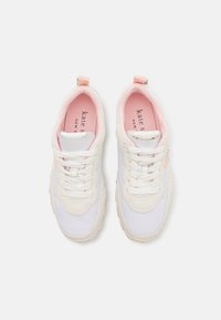Adidași din plasă albă cu accente roz, fabrică texturată, șireturi albe și o talpă din cauciuc. Brandingul este vizibil în interiorul pantofilor.