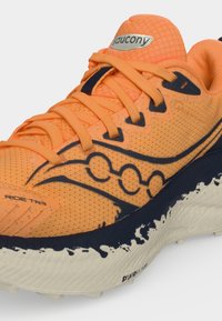 Πορτοκαλί παπούτσι τρεξίματος Saucony με μαύρες λεπτομέρειες, μαλακή σόλα και λεπτομερές πλεγμένο επάνω μέρος που δείχνει το κείμενο "Ride TR3" και "PWRRUN+".