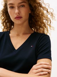 Ναυτικό μπλουζάκι V με κοντά μανίκια και μικρό λογότυπο στο στήθος. Το ύφασμα φαίνεται μαλακό με λεία υφή.