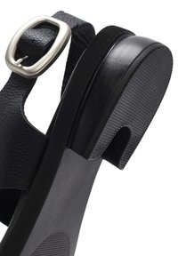Zwarte sandalen met een leren band met textuur, zilveren gesp en rubberen zool met een lichte hak en uitsnijdingen.