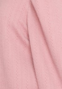 Miękka różowa tkanina z subtelnym wzorem w zygzak i splotem, przedstawiona w zbliżeniu z delikatnymi fałdami.