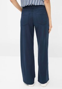 Navy wide-leg pants made of stretchy, smooth fabric with a waistband. Features two rear pockets and a relaxed, flowing design.