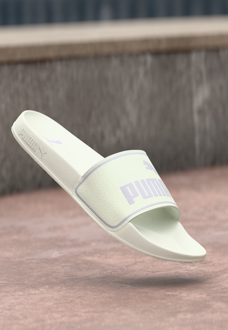 Ljusgrön slangsandal med en texturerad rem som har en lavendelfärgad logotyp. Slät fotbädd och en minimalistisk design. Lämplig för avslappnad användning.