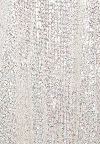 Gros plan de petits sequins argentés disposés densément sur un tissu créant une surface texturée scintillante et réfléchissante.