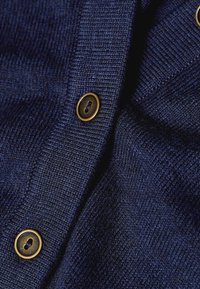 Marineblauer gestrickter Cardigan mit weicher Textur, ausgestattet mit goldfarbenen Knöpfen und Rippdetails entlang der Kanten.