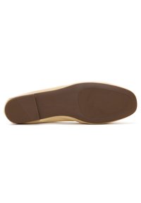 Suola delle scarpe di colore beige con una finitura liscia e opaca, caratterizzata da una suola marrone e un sottile motivo rettangolare vicino al tallone. Taglia contrassegnata come 36.
