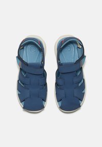 Siniset nahka-sandaalit, joissa on säädettävät hihnat, avoin varvasdesign ja vaaleansininen sisäpohja. Valkoinen kumipohja, jossa on punaisia yksityiskohtia hihnoissa.