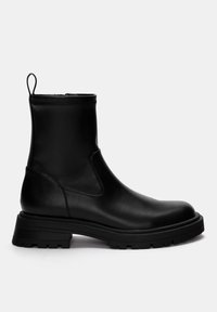Černá kožená kotníková bota s elegantním designem, kulatou špičkou, elastickými bočními panely a texturovanou, robustní gumovou podrážkou. Obsahuje poutko pro snadné obouvání.