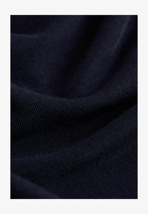 Marineblåt stof med en fin, struktureret vævning, glat overflade og blød fold, som fremhæver syningsdetaljer og dybde i farven.