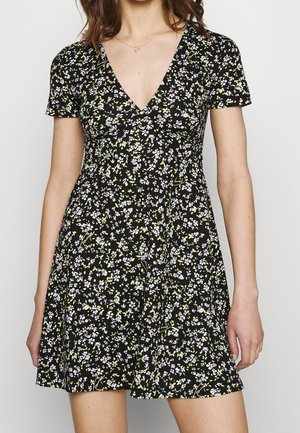 Black dress with short sleeves, v-neckline, and floral print in white, purple, and green. Flowing silhouette with a fitted waist.