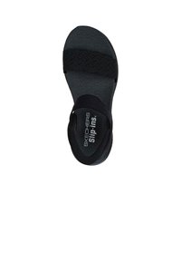 Sandalia negra Skechers de tipo slip-on con correas de tela trenzada, plantilla texturizada y suela curva. Presenta el logo en la plantilla.