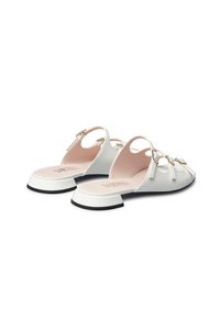 Scarpe sintetiche bianche con punta arrotondata, tacco basso a blocco e design con ritagli. Presentano dettagli in hardware dorato e un interno rosa.