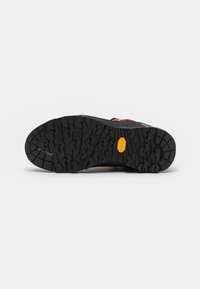 Semelle extérieure noire texturée avec un motif de semelle prononcé. Présente un logo Vibram jaune et une construction en caoutchouc durable pour une meilleure adhérence.