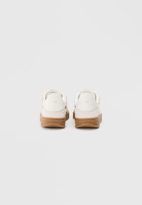 Adidași albi combinați din suede și piele, cu o talpă din cauciuc bej și un design minimalist. Vedere din spate ce evidențiază texturile netede.