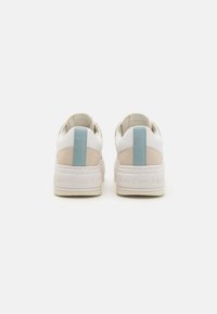 Hvite sneakers med glatt lærövre, med en lys beige aksent og en blå hælflik. Stablet såle med preget merke.