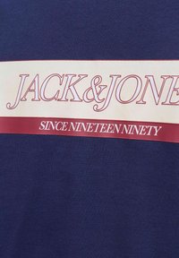 Marineblå bomulds T-shirt med fede hvide og vinrøde vandrette striber samt teksten "JACK & JONES" og "SIDEN NITTNOGEN."
