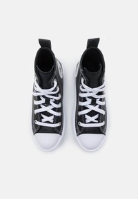 Sneaker alte nere realizzate in materiale testurizzato, con punte in gomma bianca e lacci bianchi, dotate di linguetta sul tallone e di un patch con logo.