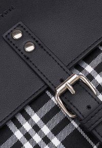 Svart lädersnodd med silverbuckle, detaljerad sömnad, över ett svart och vitt rutigt mönster. Innehåller metallnitar.