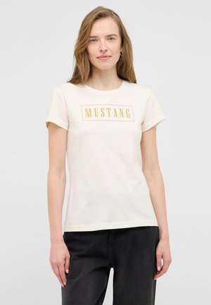 Creme farbenes Baumwoll-T-Shirt mit kurzen Ärmeln und Rundhalsausschnitt, mit einem auffälligen "MUSTANG"-Grafikdesign in Gold auf der Vorderseite.