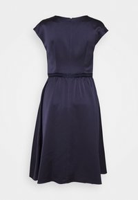 Vue arrière d'une robe bleu marine longueur genou avec des manches courtes, une taille cintrée et une légère évasée au niveau de la jupe.