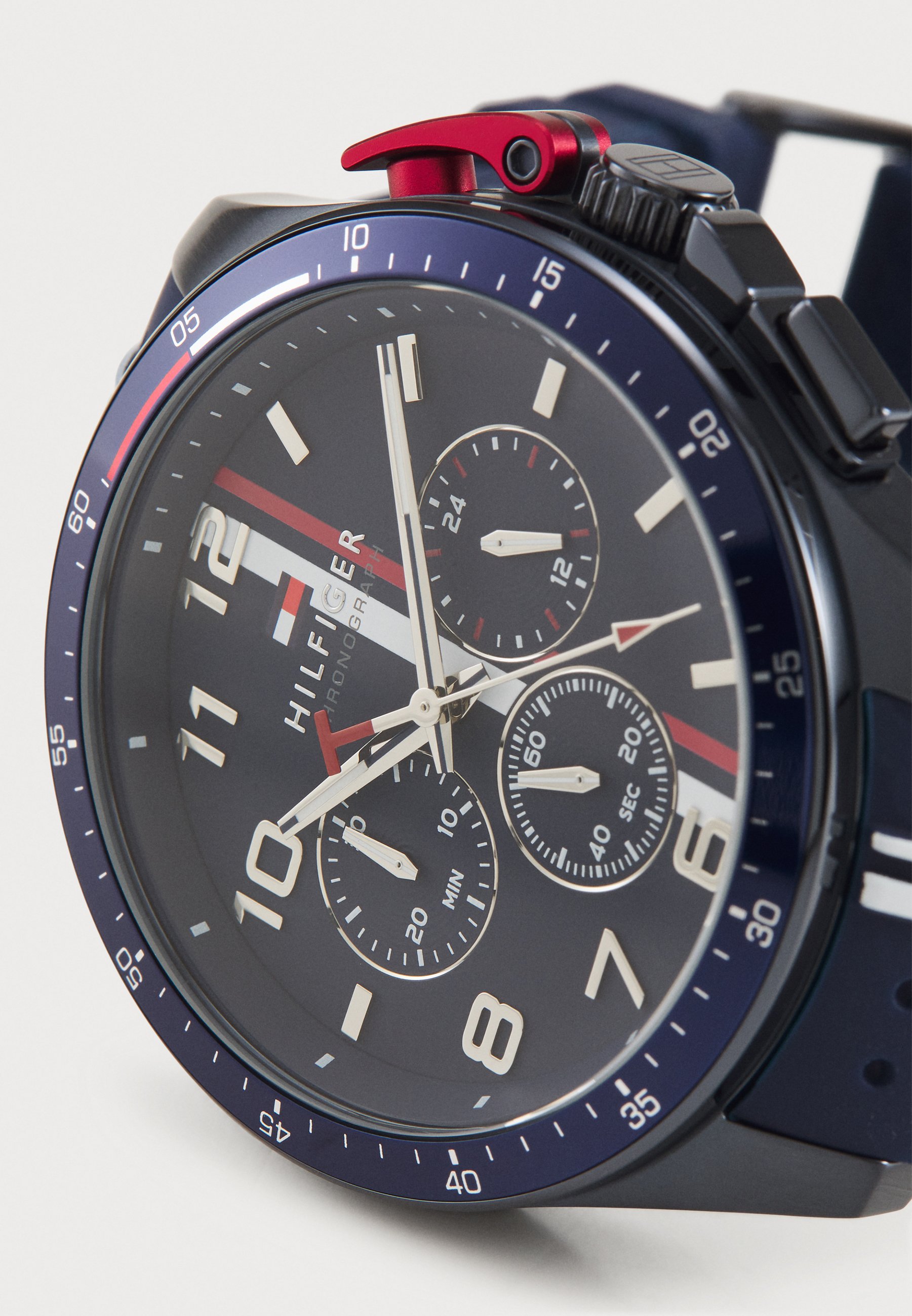 Montre chronographe noire avec un bracelet en silicone bleu marine, dotée d'une lunette bleue, de marqueurs d'heure blancs et d'accents rouges sur la couronne et le logo.