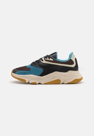 Sneaker basse en noir, bleu, marron et beige avec semelle texturée et lacets, présenté de côté sur fond blanc.