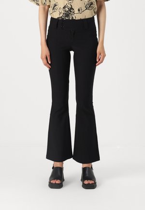 Black flared trousers with a high waistband, smooth texture, dual button closure, and a fitted silhouette that flares at the hem.
