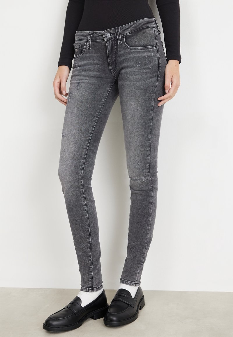 Jeans ajustados en denim gris oscuro con textura desgastada, que cuentan con un clásico diseño de cinco bolsillos y un cierre de cremallera con botón.