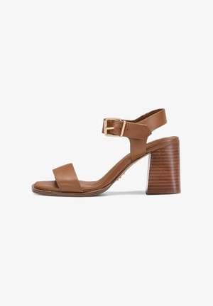 Brązowy skórzany sandał z odkrytymi palcami, paskiem wokół kostki, złotą klamrą, wyściółką na wkładce oraz grubym, wysokim, warstwowym obcasem na białym tle.