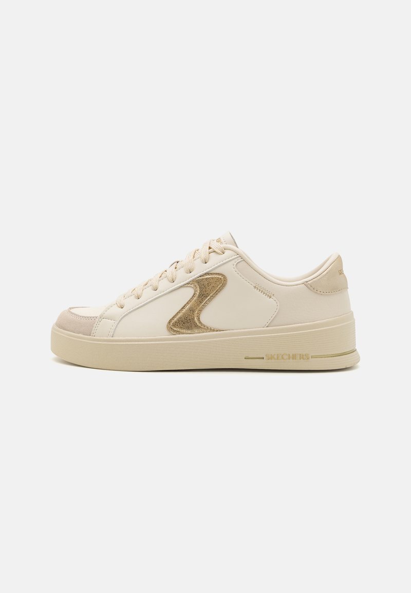 Sneaker beige con tomaia in pelle liscia, punta in suede e logo con accento dorato. Presentano lacci piatti e una suola in gomma testurizzata.