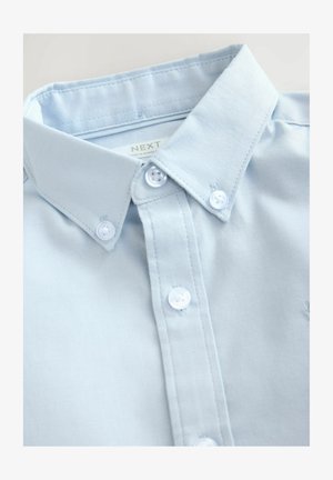 Hele sinine nööbitav särk, millel on struktureeritud krae, valged nööbid ja tekstureeritud kangas. Sildi on nähtav krae sees.