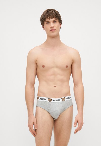 Sive bombažna spodnjica z belim pasom, na katerem je logotip medveda in besedilo "MOSCHINO". Oblika, ki se prilega telesu, gladka tekstura in elastičen pas.