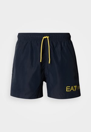 Tmavomodré plavecké šortky s elastickým pásom a žltou šnúrkou. Na prednej strane je žlté logo „EA7“ a bočné vrecká.