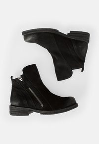 Botines negros de ante con cierre de cremallera, tacón bajo apilado, puntera redondeada y suelas texturizadas. Superficie suave con acentos suaves.