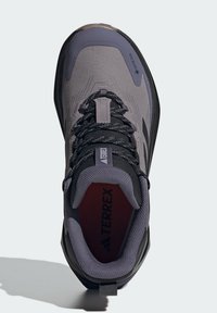 Chaussure de randonnée grise avec une tige en tissu texturé, des lacets noirs et un col rembourré. Présente l'étiquette GORE-TEX et des accents de semelle intérieure rouges.