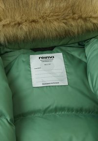 Zielona kurtka puchowa w środku z brązowym sztucznym futrem. Metka wyświetla markę "reima", rozmiar 92/2T i instrukcje dotyczące pielęgnacji. Miękka faktura.