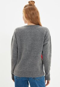 Grauer Pullover mit einer weichen Textur, mit rundem Ausschnitt und ribbed Bündchen. Die Rückseite zeigt ein schlichteres Design ohne zusätzliche Details.