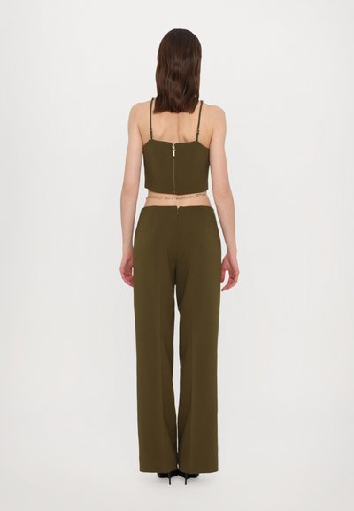 Top scurt de culoare verde măslin, cu bretele subțiri și fermoar la spate, asortat cu pantaloni largi, cu talie înaltă, în aceeași culoare. Textură netedă.