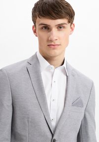 Hellgrauer Blazer mit strukturiertem Stoff, einreihigem Design, Reverskragen und einem gemusterten Einstecktuch in Blautönen.