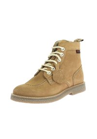 Stivaletti alla caviglia in suede beige con lacci bianchi, punta tonda e suola in gomma. Presentano un'etichetta decorativa sul lato e dettagli di cucitura.
