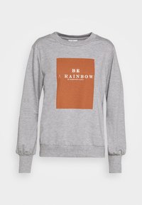 Grå sweatshirt med rund halsringning och långa, puffiga ärmar. Har en rektangulär grafisk tryck i rostfärg med vit text som säger "VAR EN REGNBÅGE I NÅGONS MOLN."