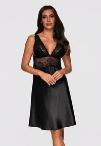 Camicia da notte in satin nero con pannelli in pizzo sul corpetto, scollatura a V e spalline regolabili. Forma fluida che arriva sopra il ginocchio.