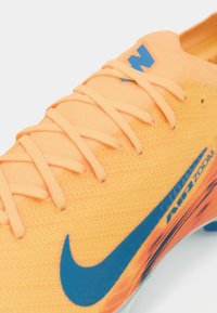 Nike Air Zoom futbolo batai ryškiai oranžinės spalvos tinkleliu, su mėlynomis detalėmis. Yra tekstūruota paviršiaus medžiaga ir raištelių sistema, užtikrinanti tvirtą prigludimą.