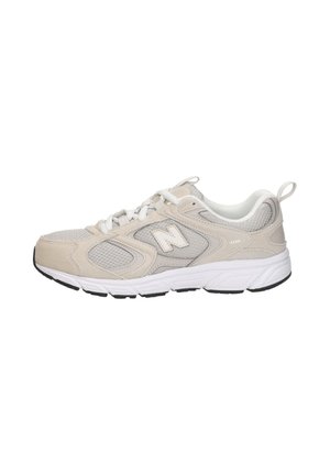 Chaussure de course New Balance beige et grise avec des lacets blancs, des panneaux en maille, et une semelle blanche amortie sur fond blanc.