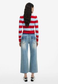 Röd och ljusblå randig tröja med en cropped design i kombination med ljusblå vida jeans med blekta områden och bakfickor.