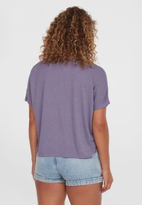 Lilla, kortærmet top med en afslappet pasform, lavet af blødt materiale, parret med lyseblå denimshorts. Glat tekstur og afslappet design.