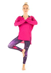 Roze langemouwen top met een relaxte pasvorm en zijsplitten, gecombineerd met paarse leggings met een sterrenstelselpatroon dat sterren en draaiende ontwerpen bevat.